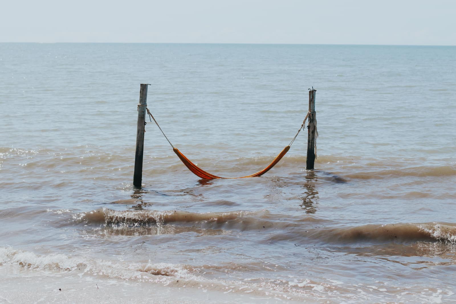 A hammock hanging by a quiet shoreline
