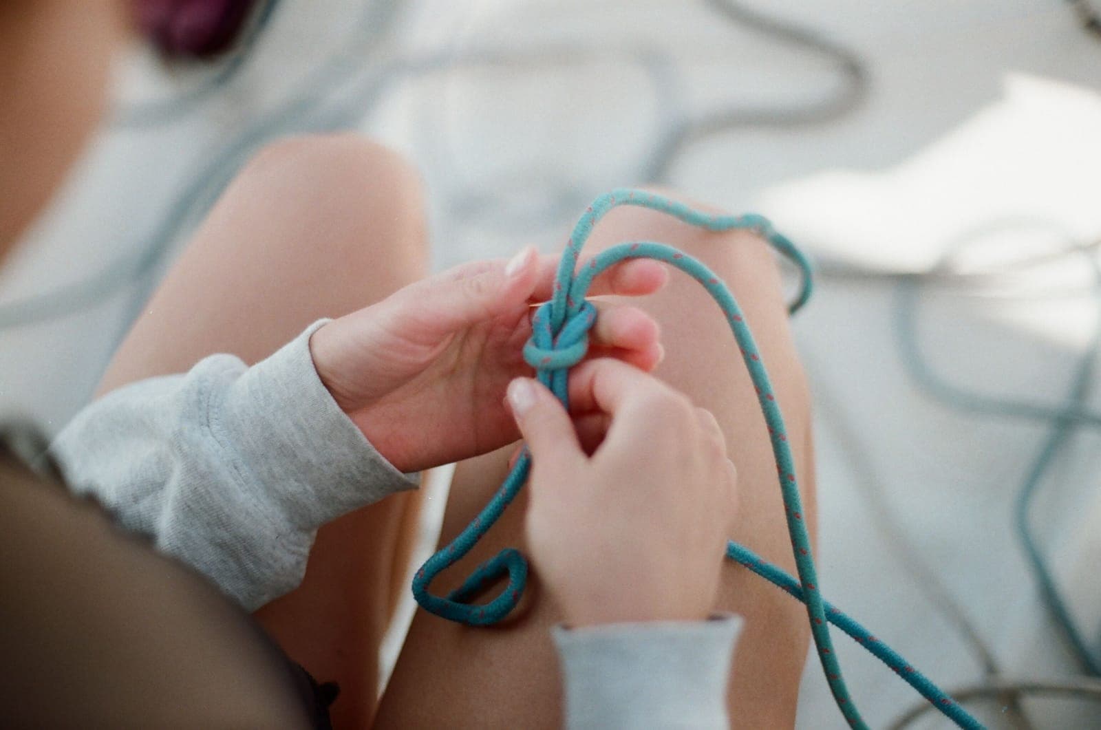 Hands working with hammock suspension cord outdoors