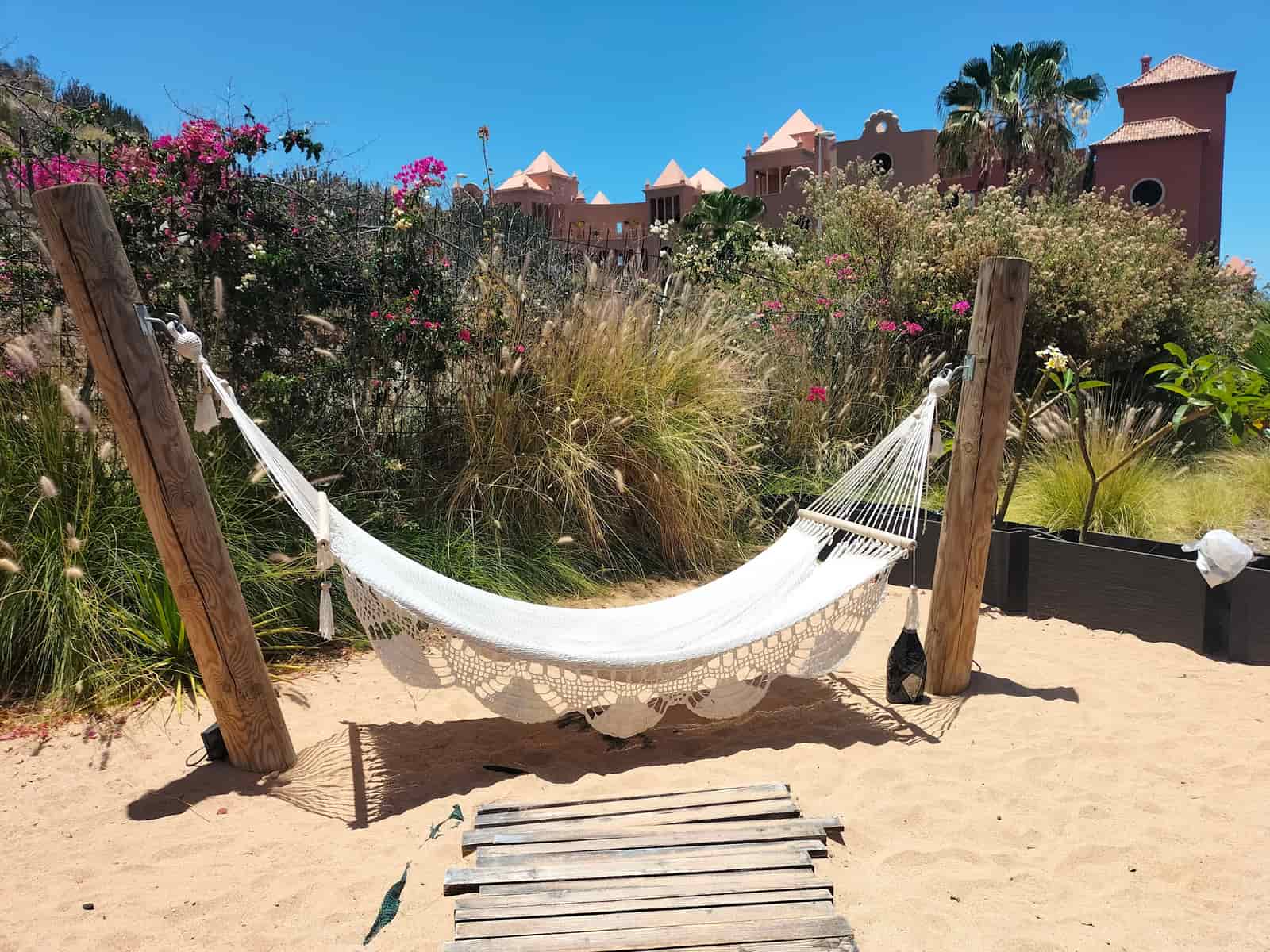 Quilted fabric hammock with wooden spreader bars in a garden